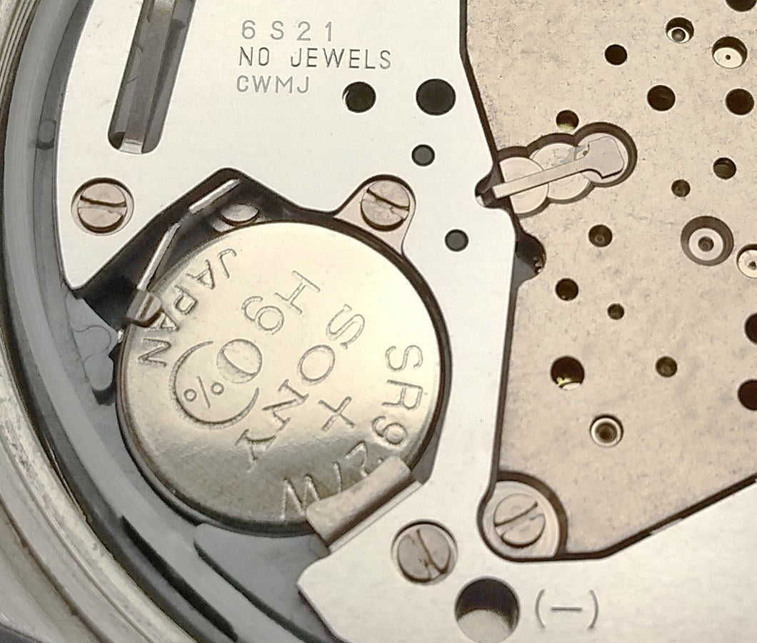 The silver oxide cell inside a quartz watch, held by its clamp