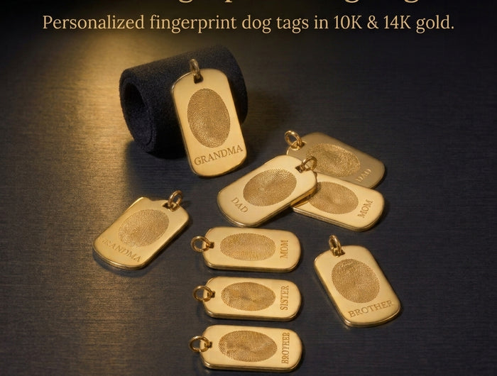 Gold fingerprint dog tags displayed on a dark textured surface, with one tag attached to a black ribbon and several tags arranged around it. Text at the top reads 'Gold Fingerprint Dog Tags.